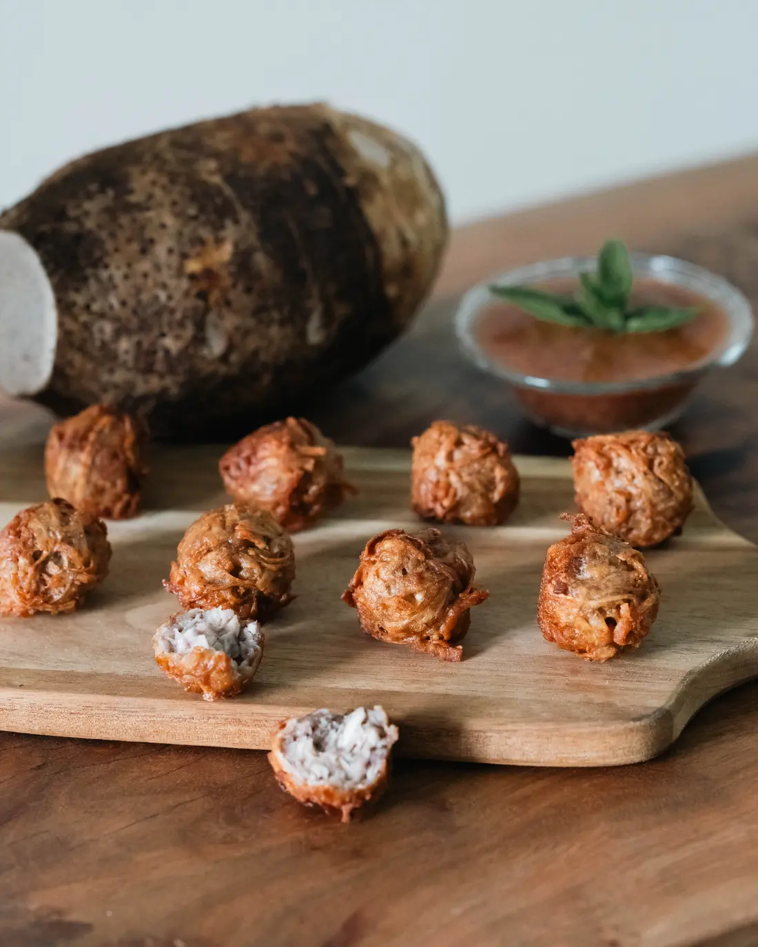A whole taro root beside freshly fried gato arouille and a bowl of chutney